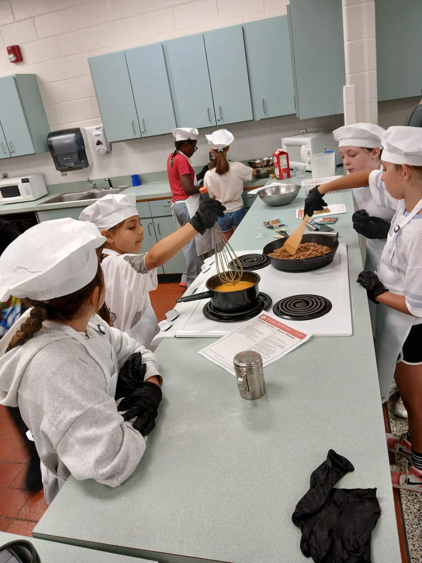 Students whisking and cooking at the stove during a Food Fun Club session