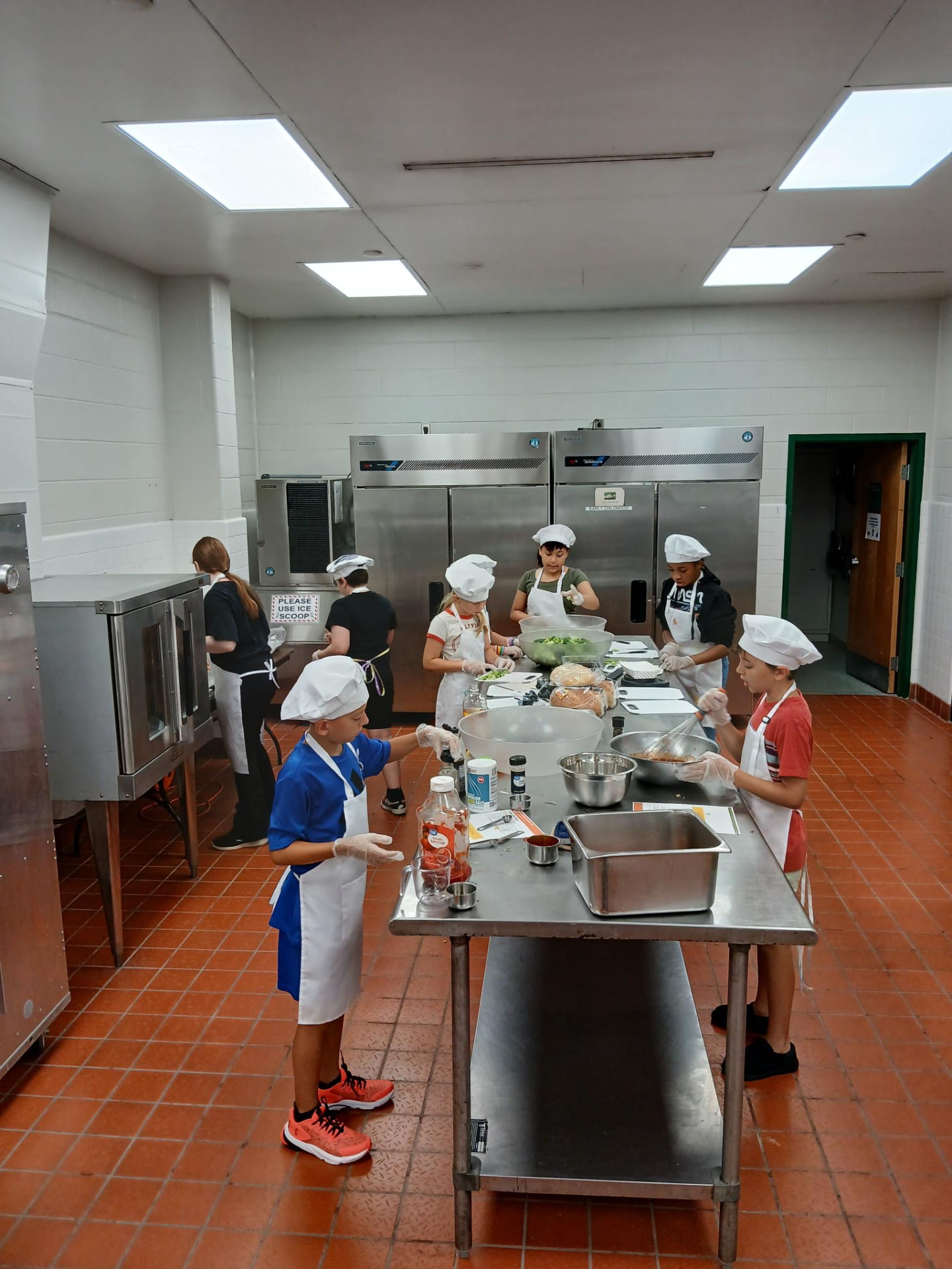 Young chefs in aprons and hats preparing ingredients together in the kitchen